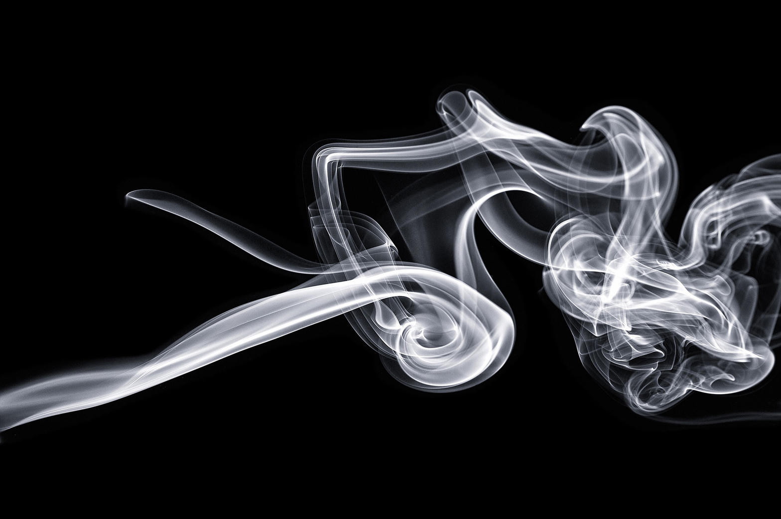 White smoke curling from a smooth stream into tangled eddies against black.